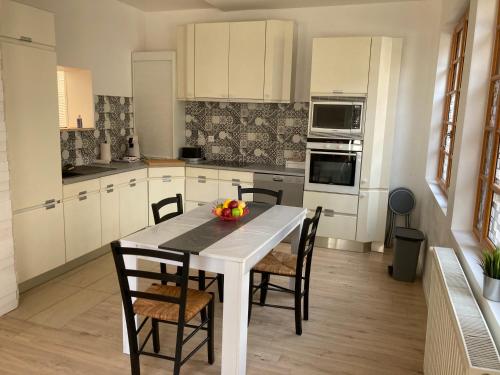 une cuisine avec une table blanche et des chaises dans l'établissement Maison au coeur d'un village, à Sainte-Foy-la-Grande