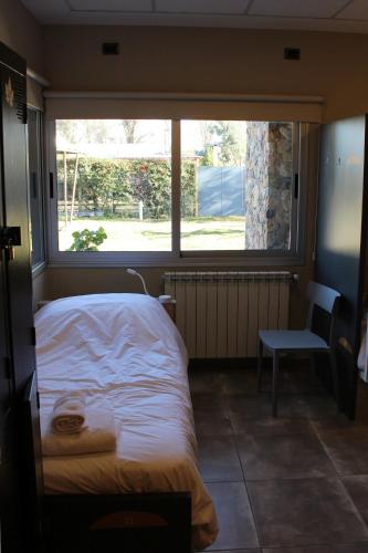 a bedroom with a bed and a window and a chair at Alojamiento Traslaviña in Vista Flores