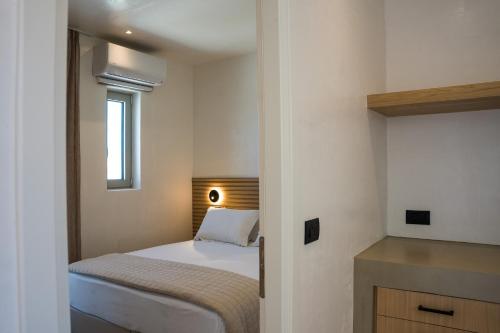 a small bedroom with a bed and a window at Wabi Aegean Villa in Ios Chora