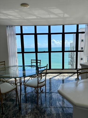 a glass table and chairs in a room with a large window at Hotel Brasil Tropical in Fortaleza