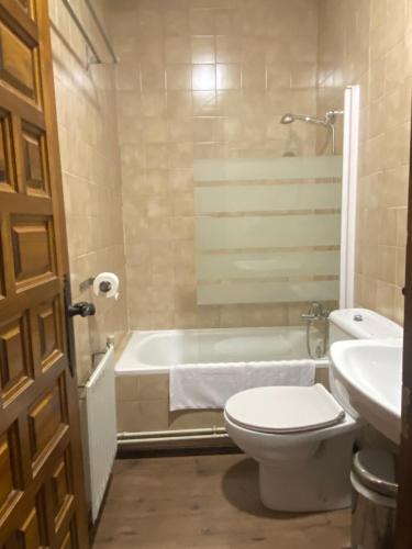 a bathroom with a tub and a toilet and a sink at Hostal Altajo con Restaurante, Naturaleza & Descanso en el Alto Tajo in Peralejos de las Truchas