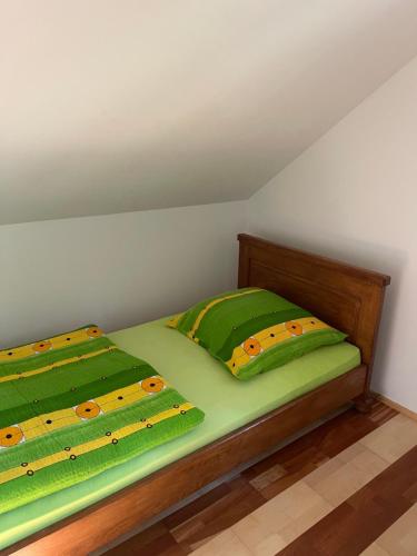 a bed with two green pillows on top of it at Domek Letniskowy w Krzemiennej in Krzemienna