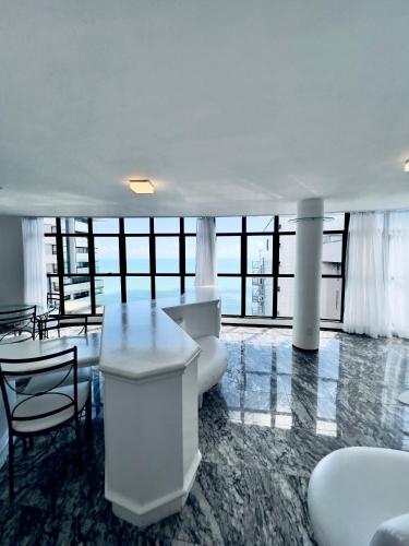 a white room with a table and chairs and windows at Hotel Brasil Tropical in Fortaleza