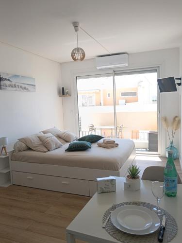 Cette chambre blanche dispose d'un lit et d'une table. dans l'établissement Studio tout confort avec place de parking et wifi, à Balaruc-les-Bains