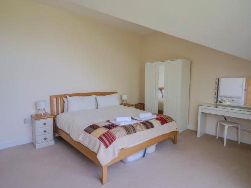 a bedroom with a bed and a desk and a mirror at Fig Tree House in Axminster