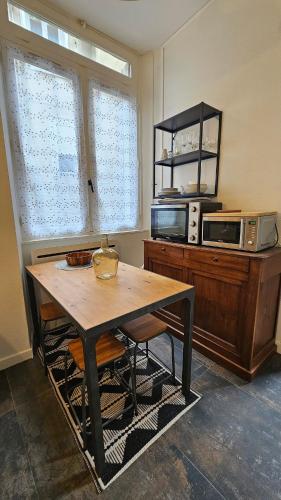 une cuisine avec une table en bois et un micro-ondes dans l'établissement Le clos Medieval - 2 bedrooms, Wi-Fi, terrace, à Montluçon