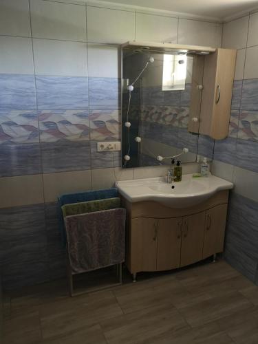 a bathroom with a sink and a mirror and a chair at Ezüstfenyő Vendégház in Sárvár