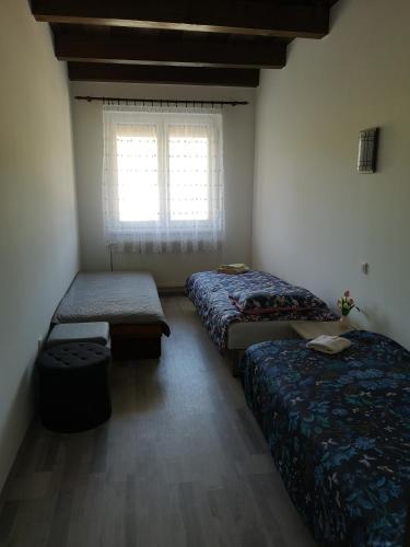 a room with three beds and a window with at Ezüstfenyő Vendégház in Sárvár