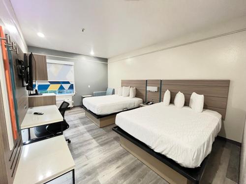 a hotel room with two beds and a desk at Sonesta Essential North Houston in Houston
