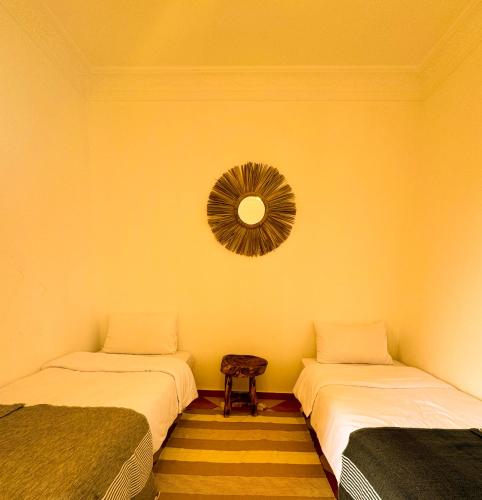 two beds in a room with a mirror on the wall at Olas Surf Camp in Imsouane