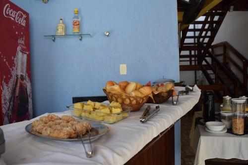 a table with baskets of bread and pastries on it at Hotel Pousada Encanto de Itapoan in Salvador