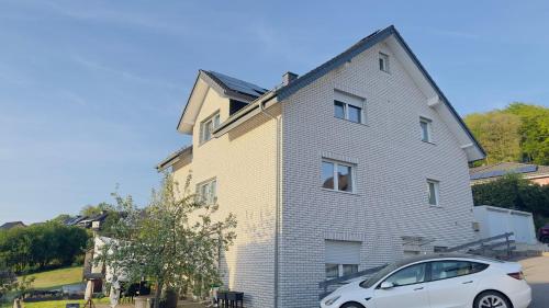 a white car parked in front of a house at Ferienwohnung in Eckenhagen in Reichshof 