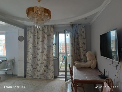 ein Teddybär sitzt auf einem Tisch in einem Wohnzimmer in der Unterkunft Жунисова 14 in Zhezdi