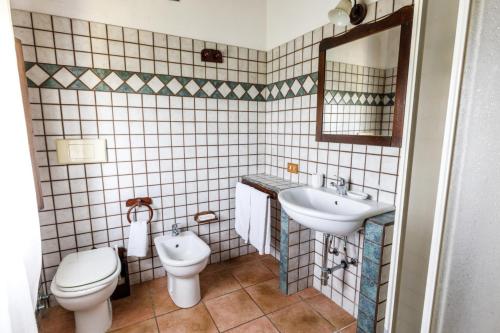 un bagno con lavandino, WC e specchio di b Giagumeddu 09A Bilo a Badesi