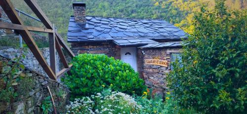 a stone house with a white door in a garden at Casa do Salgueirinho in Casal do Rei