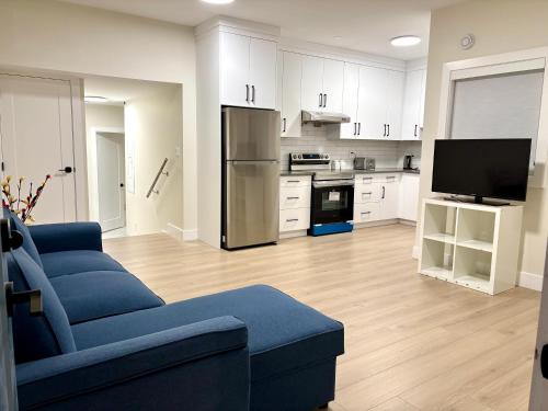 a living room with a blue couch and a kitchen at Sunny White Rock 2BR, Steps to Sand, Brand New Stay in White Rock