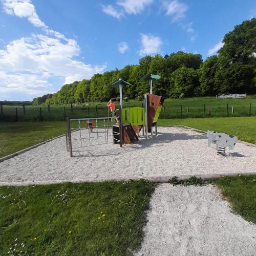 a playground in a field with a person in the background at La closerie aux écureuils in Limeux