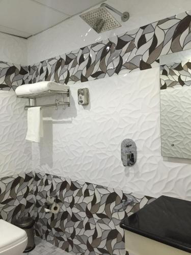a bathroom with a toilet and a patterned wall at Daffodils Spice Court in Cochin