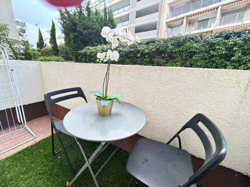 une table et des chaises avec un vase de fleurs. dans l'établissement Cosy- 4 pers Hyper Centre - Plage à 2 min à pied, à Saint-Raphaël