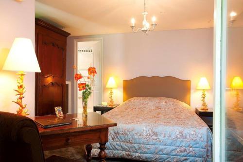a bedroom with a bed and a desk and a table with flowers at Château de Fleurville & Spa in Fleurville
