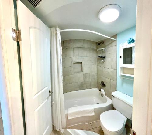 a bathroom with a white tub and a toilet at Beach Condo with Pool & Tiki Bar! in Daytona Beach