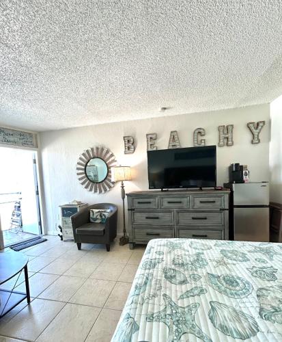 a bedroom with a bed and a flat screen tv at Beach Condo with Pool & Tiki Bar! in Daytona Beach