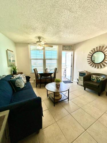 a living room with a blue couch and a table at Beach Condo with Pool & Tiki Bar! in Daytona Beach