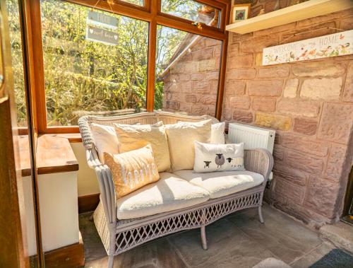 a wicker chair sitting on a porch with pillows at Willow cottage with private hot tub in Upper Hulme