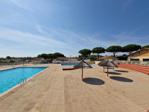 une piscine avec des parasols à côté d'une piscine dans l'établissement Pavillon 3 chambres dans résidence avec piscine, à Vendres