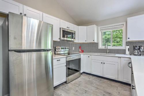 a kitchen with white cabinets and a stainless steel refrigerator at Creek Front Pocono Mountain Getaway with Game room & Sauna in Tobyhanna