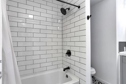 a white tiled bathroom with a tub and a toilet at Creek Front Pocono Mountain Getaway with Game room & Sauna in Tobyhanna