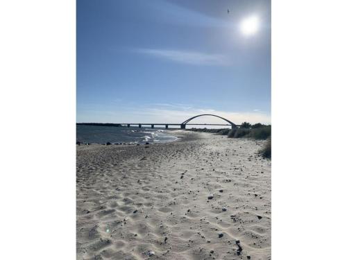 a sandy beach with a bridge in the background at Island Nest Modern Retreat in Fehmarn