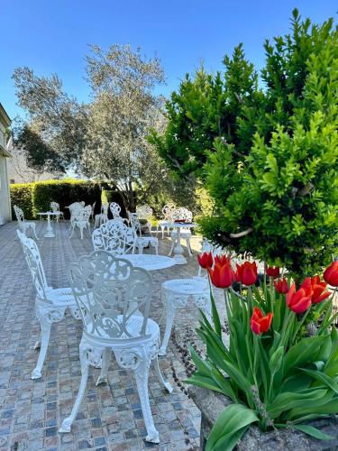 a patio with white tables and chairs and red tulips at Logis Demeure de la Vignole in Turquant