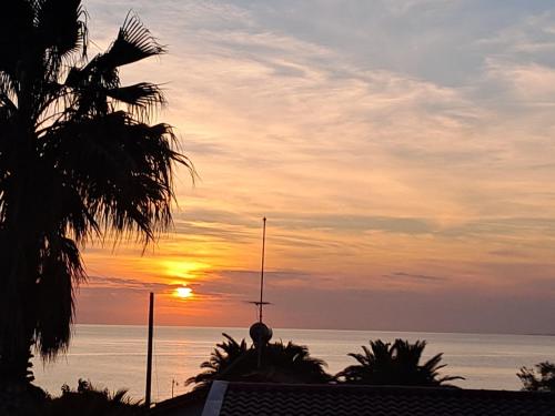a sunset over the ocean with a building and palm trees at Evilion- Potidaia- Halkidiki- 100m from the sea in Nea Potidaea