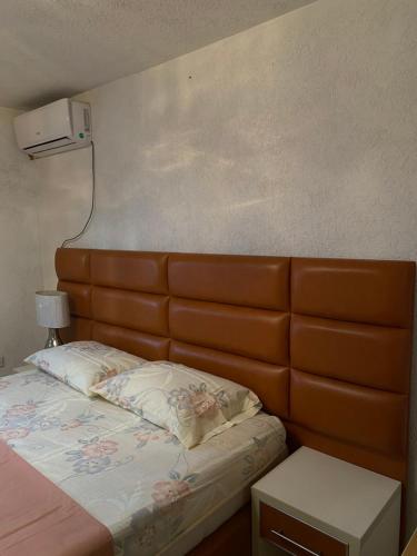 a bed with a brown padded headboard in a room at Centerside Apartment in Ulcinj