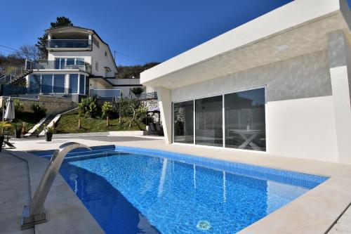 a villa with a swimming pool in front of a house at House Luxury in Matulji