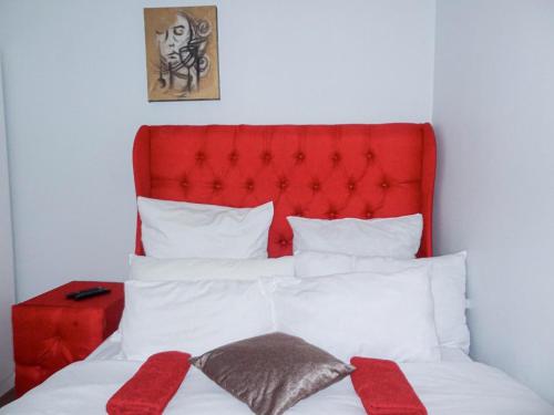 a bed with a red headboard and two red pillows at BKaap1 Queens and Kings Guest House in Cape Town