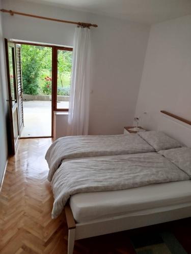 a white bedroom with a bed with a window at Brine in Starigrad-Paklenica