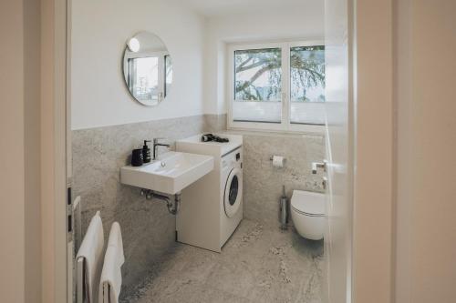 a bathroom with a sink and a washing machine at Apart Suites Gravbach in Lagundo