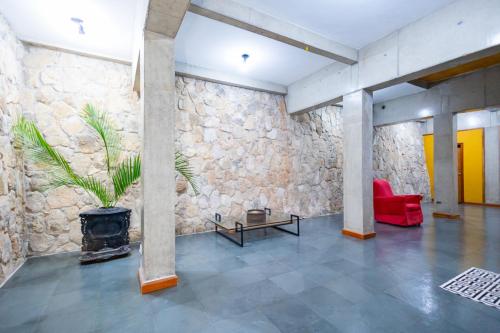 a living room with a stone wall and a red chair at Putini Pousada e Hotel by OYO in São Roque