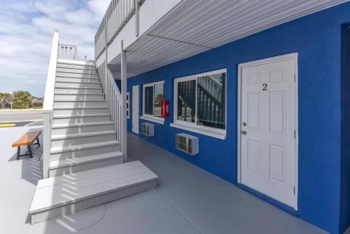 a blue building with stairs and a white door at Modern King Suite #12 - Steps to Beach in Daytona Beach