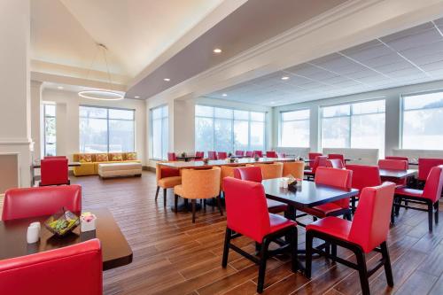 a dining room with red chairs and tables and windows at Hilton Garden Inn Tampa Northwest/Oldsmar in Oldsmar