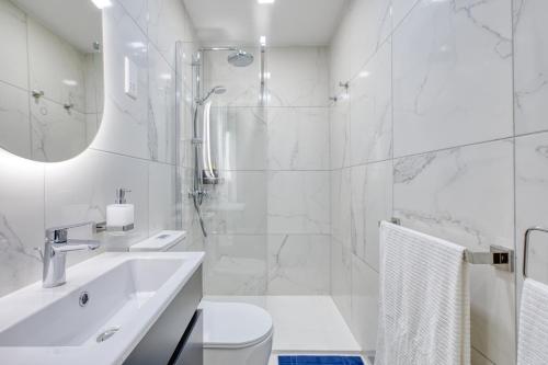 a white bathroom with a shower and a sink at Hughesville Birgu in Birgu