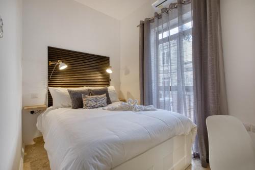 a bedroom with a large white bed with a window at Hughesville Birgu in Birgu