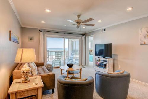 een woonkamer met een bank, stoelen en een televisie bij Queen's Grant A-201 in Topsail Beach