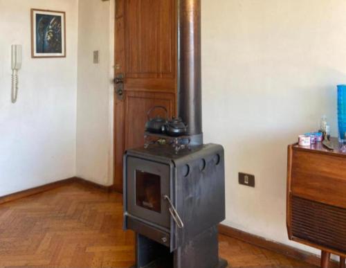 a black stove in a room with a wooden floor at Lindo Departamento Centro in Osorno