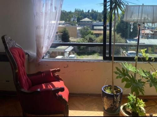 a red chair sitting in front of a window at Lindo Departamento Centro in Osorno