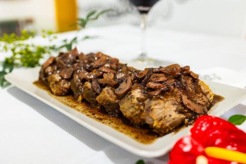 a plate of meat with chocolate sauce and strawberries on a table at Putini Pousada e Hotel by OYO in São Roque