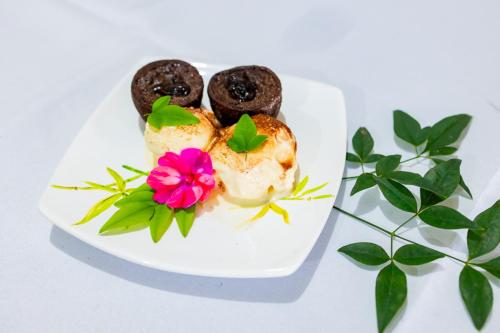 a plate of food with donuts and a pink flower at Putini Pousada e Hotel by OYO in São Roque