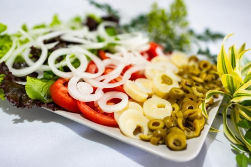 a plate of food with vegetables on a table at Putini Pousada e Hotel by OYO in São Roque